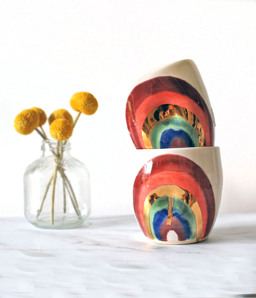 Two ceramic tumblers with colorful rainbow design. 