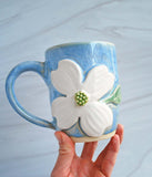 Ceramic mug in blue glaze with white dogwood flower