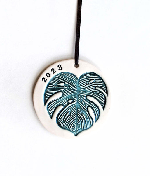 Monstera Leaf Ornament, 2023Monstera leaf ornament, in green and white. 2023 is stamped. Add metallic gold luster for a special shine on your tree. This ornament can also be customized with a n