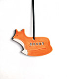 Ceramic ornament, shaped like a fox. Glazed in orange and white. With name stamped in black. 