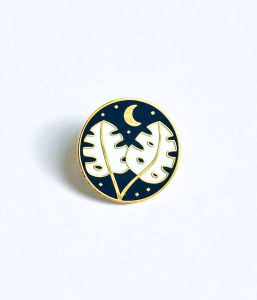 Monstera Leaf Enamel PinMonstera leaf and moon hard enamel cloisonné pin. This high-polished pin has a navy blue background, with white leaves, and gold accents. Add some beautiful bling to