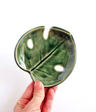 Handmade ceramic monstera-leaf shaped leaf. In bright green glaze